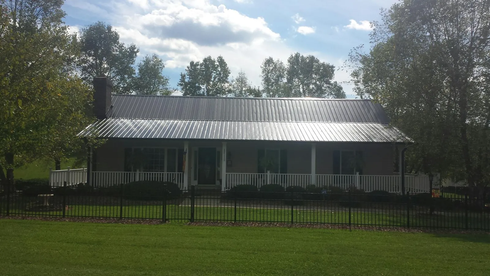 Gray metal roof on a brick ranch with a full width front porch — Gutter Guard Installation work by our crew in Chester